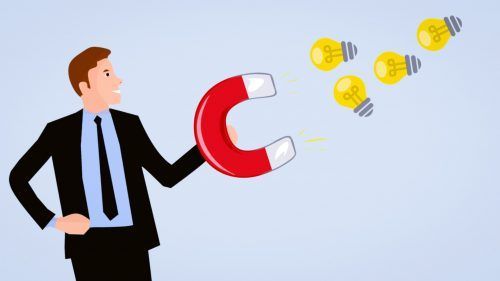 Hombre de negocios sosteniendo un imán rojo que atrae bombillas amarillas representando ideas