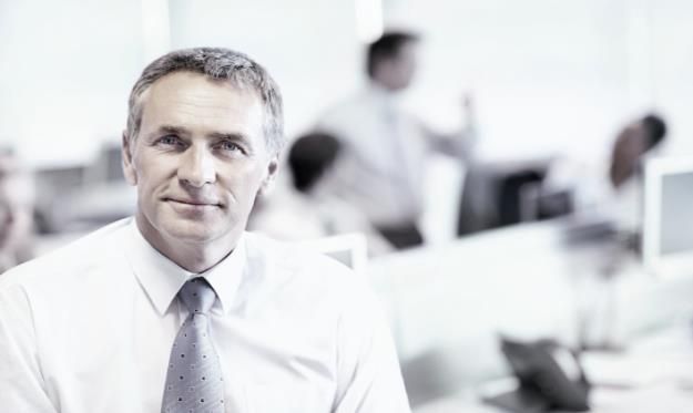 Hombre de negocios canoso con camisa blanca y corbata gris en oficina moderna